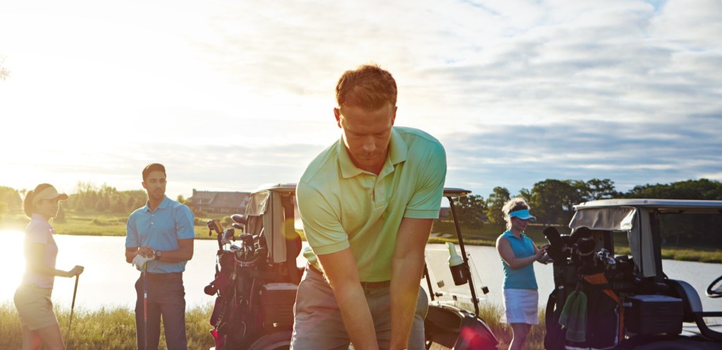 Golfer taking a swing on golf course 